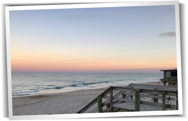 a morning view of the ocean, with stairs leading down to the beach